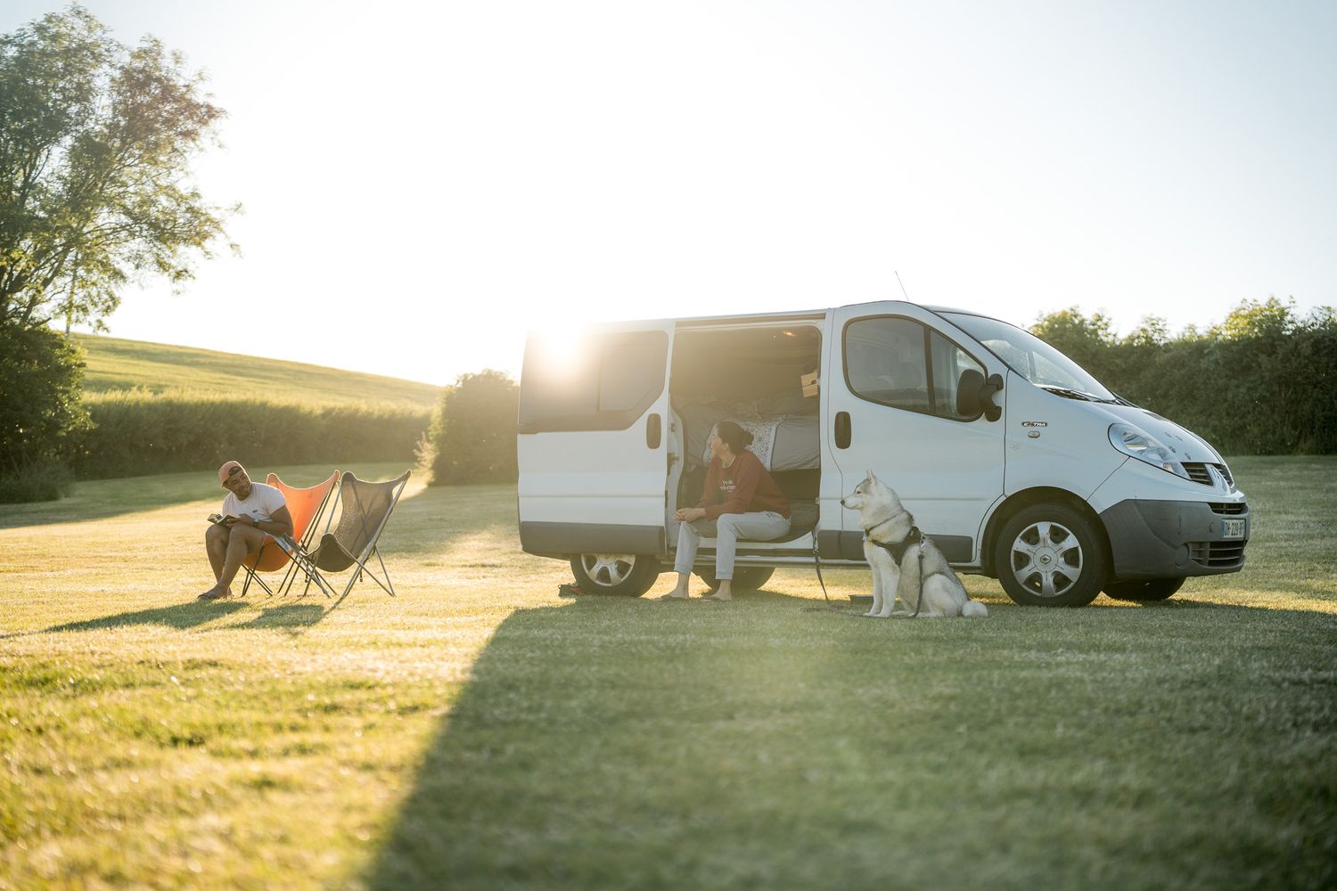 couple avec leur chien devant leur van au coucher du soleil