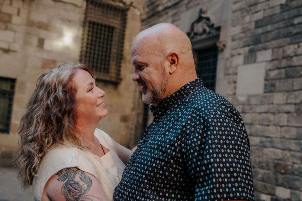 Joyful couple holding hands walking down narrow ancient street.