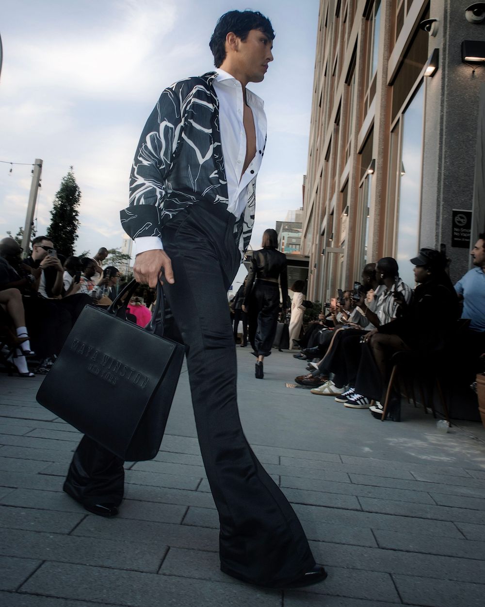 Low-angle shots of models walking in dark formal wear against an urban backdrop.