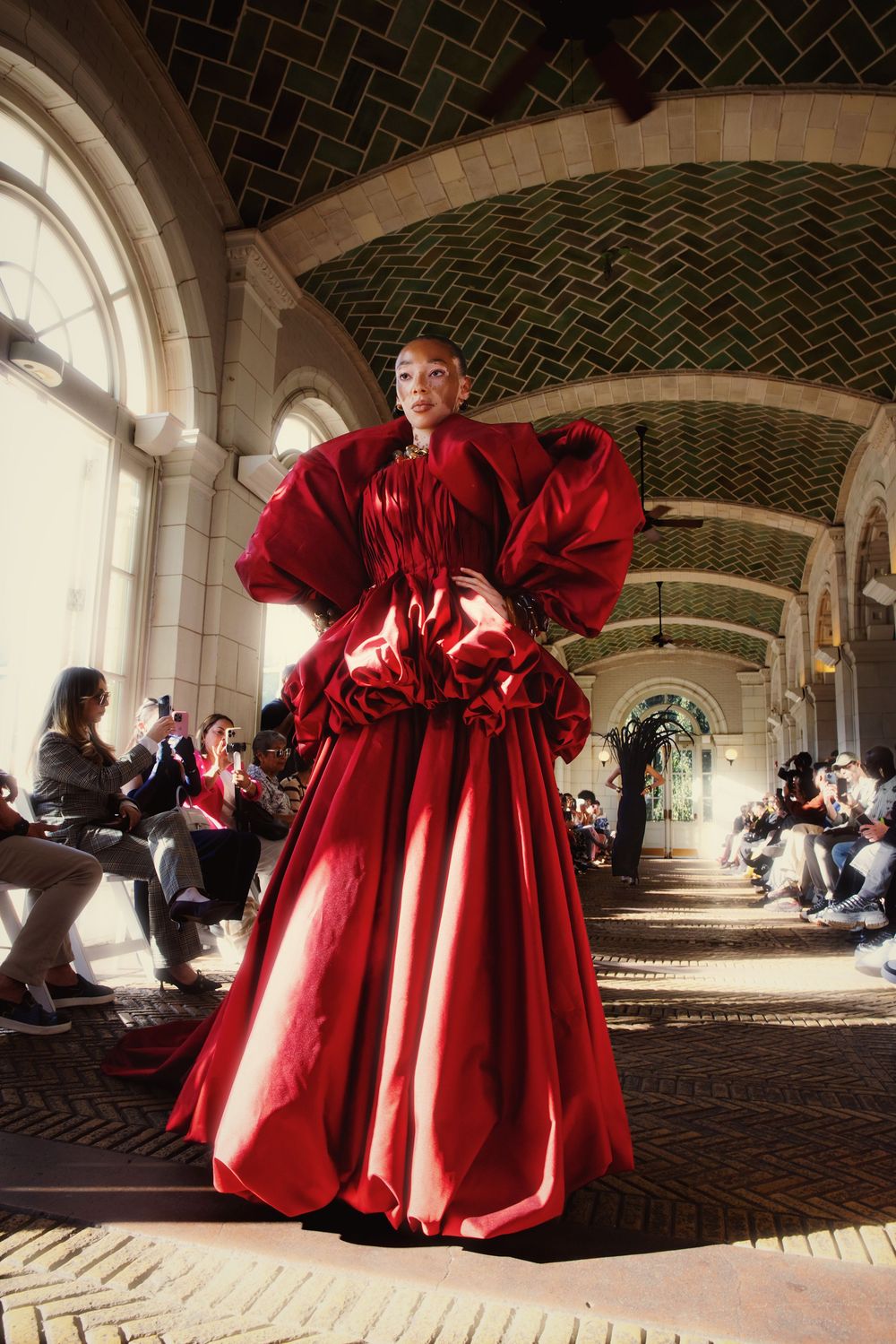 A figure in flowing red robes spins and twirls under an arched stone passageway with dramatic lighting.