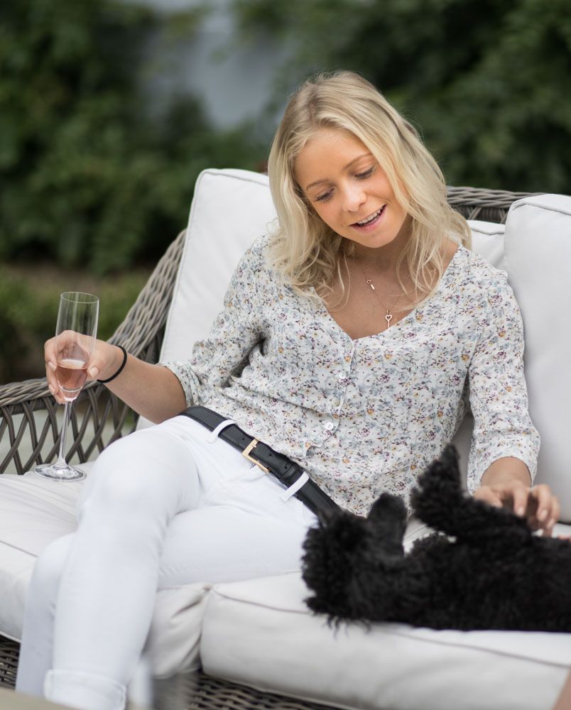 Family portrait of young female relaxing on outdoor sofa with small black dog