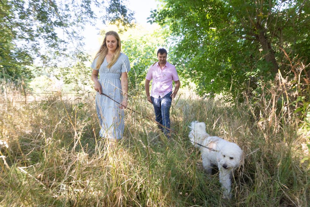 Couple walking their dog through long grass