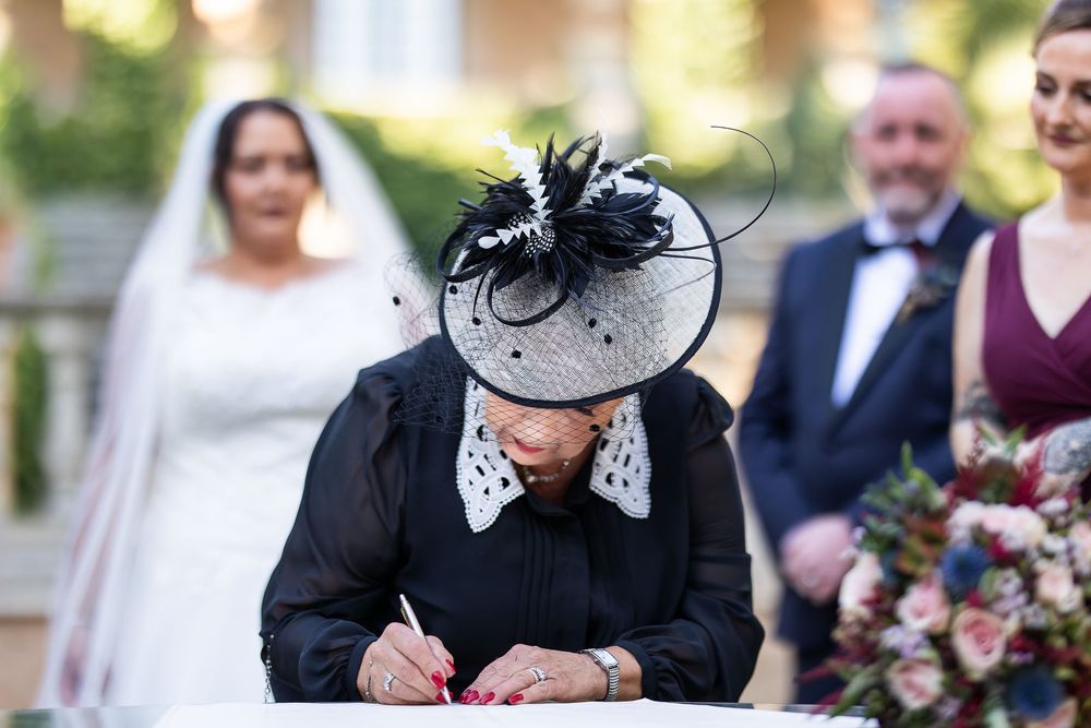 Mother of bride signs register as bride looks on