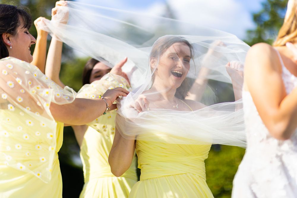 Bridesmaids joking and playing with bride's veil