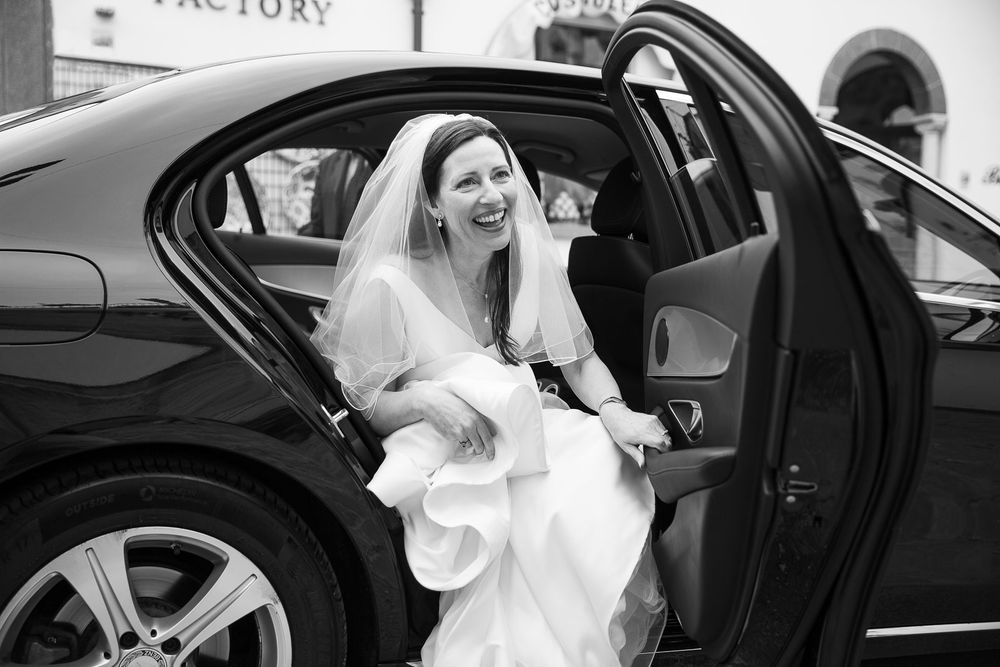 Bride getting out of wedding car at historic church