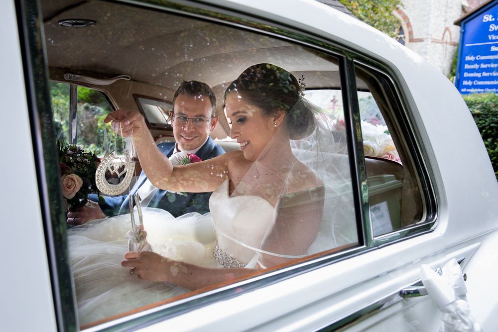 Bride and groom share a moment in Rolls Royce outside historic church