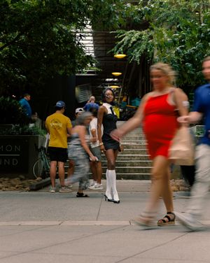 People walking and climbing outdoor stairs in an urban park setting with greenery and trees.