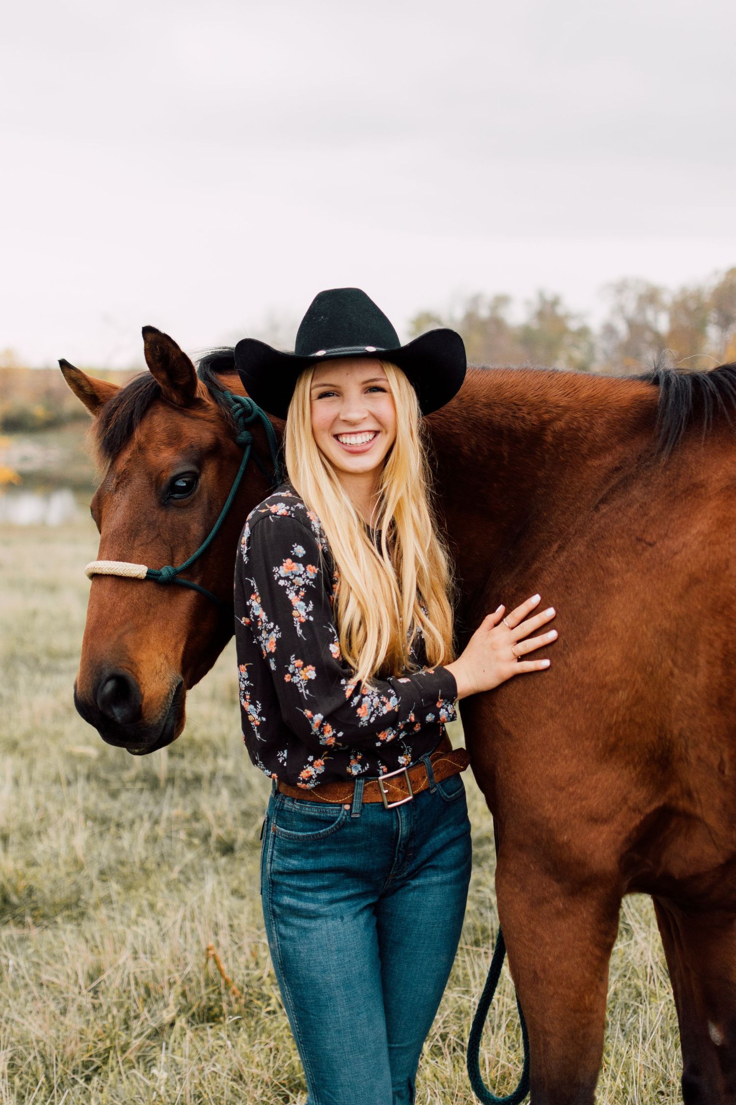 Country western photoshoot with a brown horse in a grassy field on an overcast day.