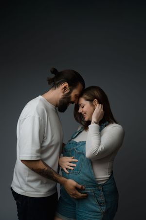 A tender moment shared between two people in white and denim against a dark background.