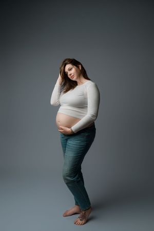 A series of five maternity photos with a pregnant person in a white top and olive pants against a gray background.