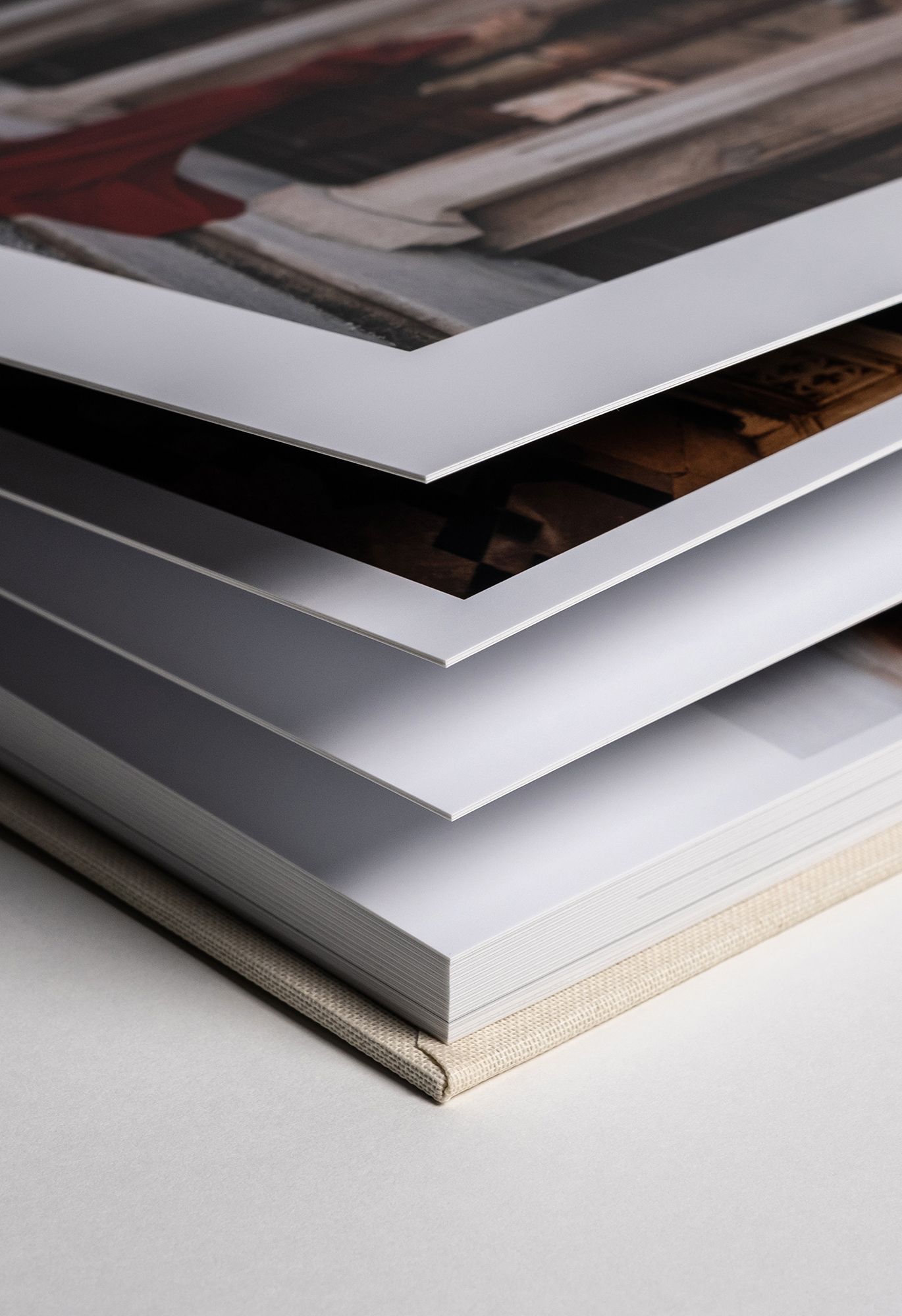 Stack of white photo albums or portfolio books with layered edges showing different thicknesses.