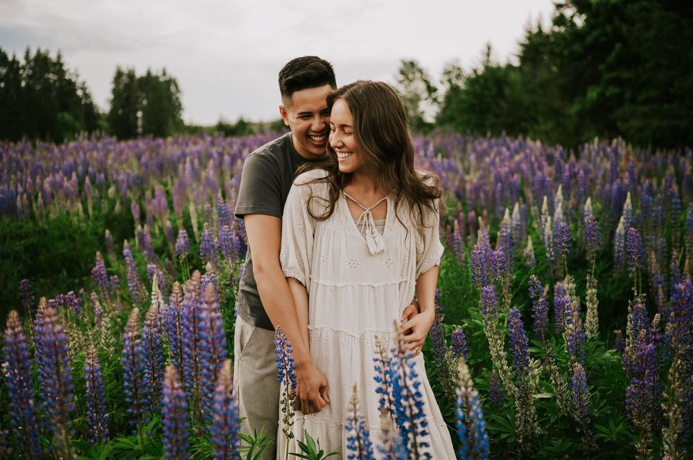 Couple snuggling and laughing in lupine field Comox Valley wildflower field locations Photography by Photographer Soulfull Photographs