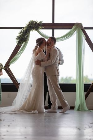 Wedding couple shares intimate moments in a bright indoor venue with mint green draping.