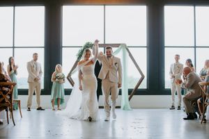 Wedding party poses in a bright indoor venue with large windows and natural light.