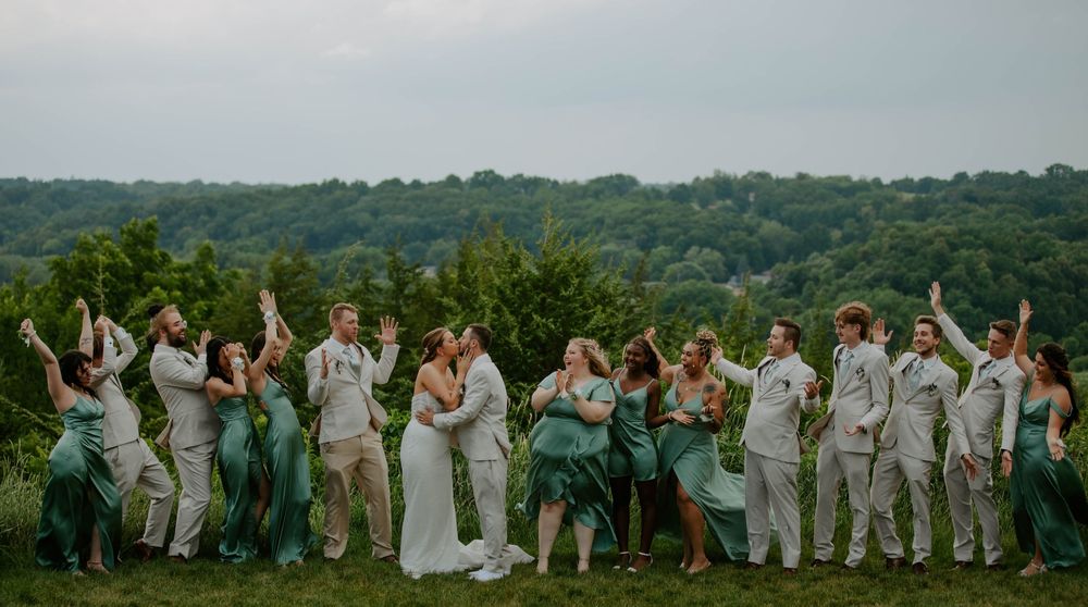 Large group photo of wedding party members standing in a line outdoors.