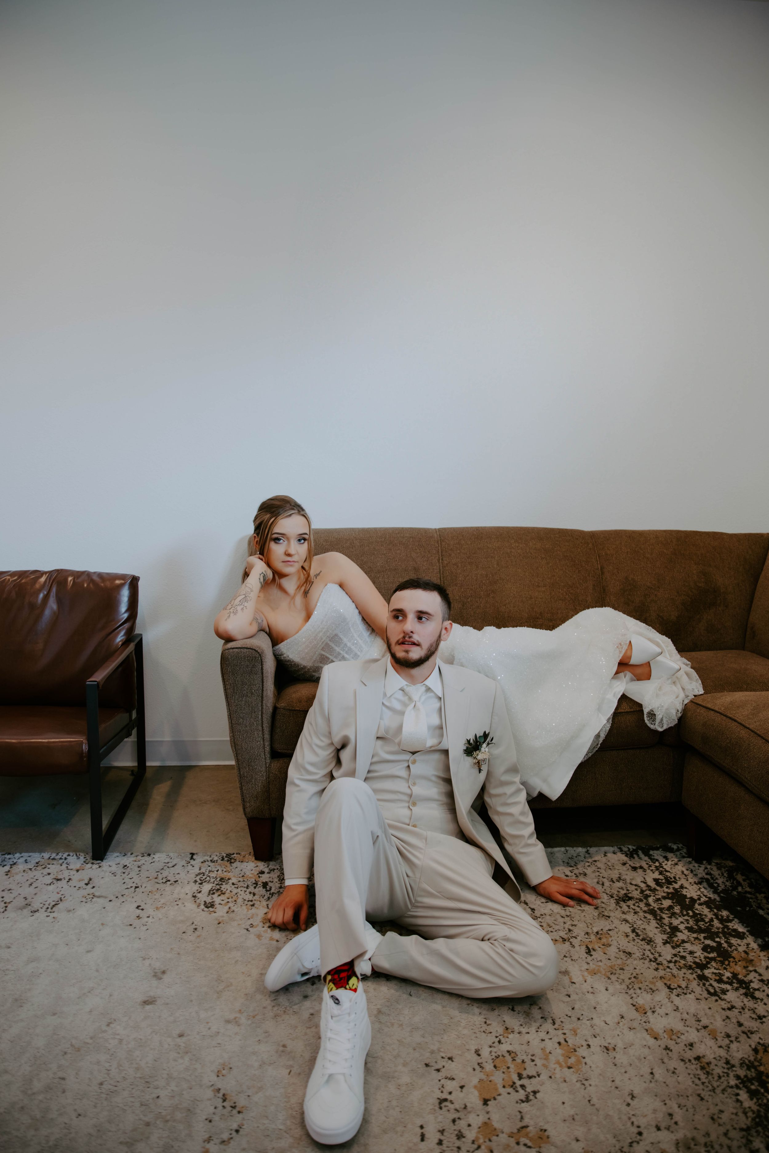 Artistic wedding photo sequence showing someone lounging on a brown couch in a light colored suit.