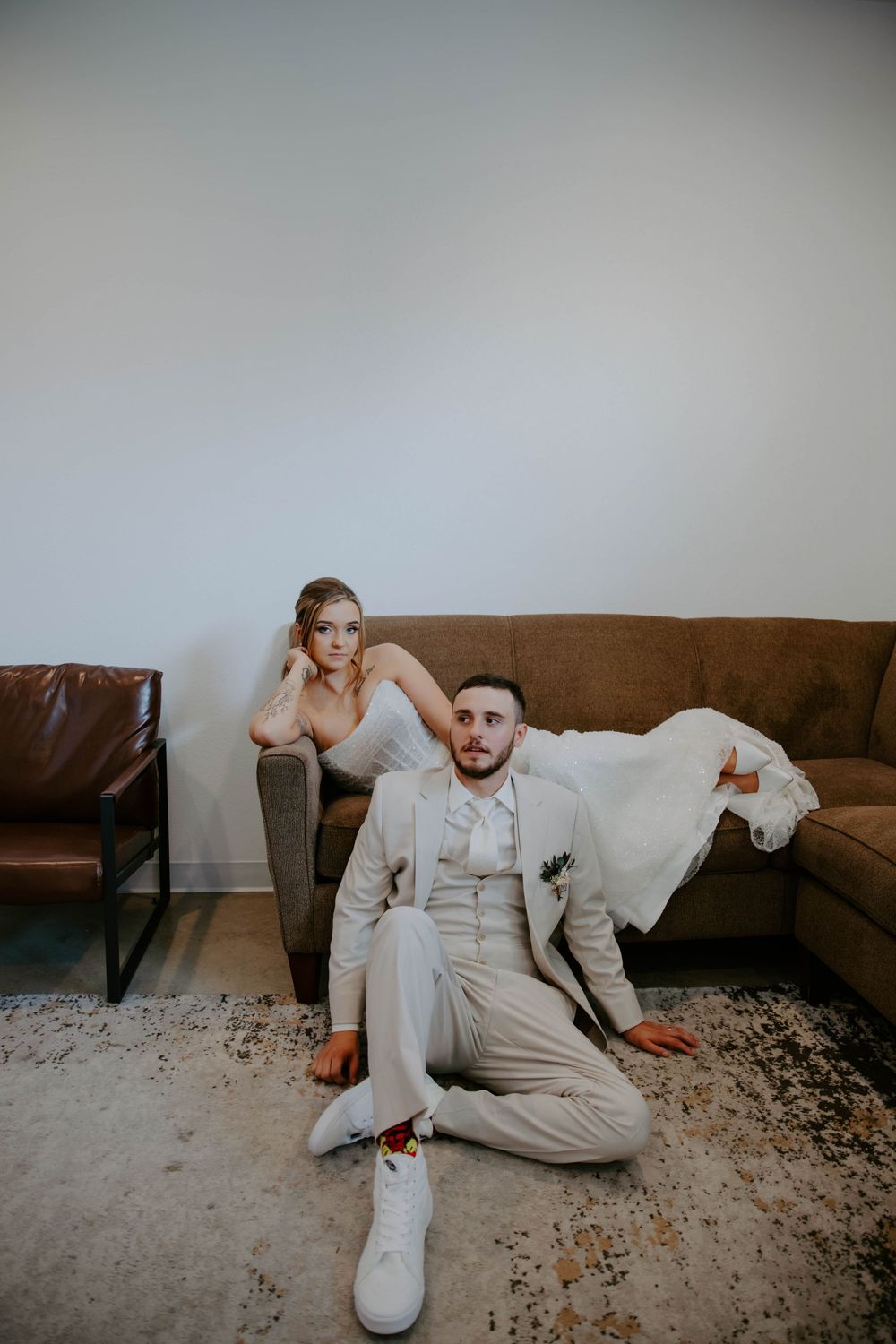 Artistic wedding photo sequence showing someone lounging on a brown couch in a light colored suit.