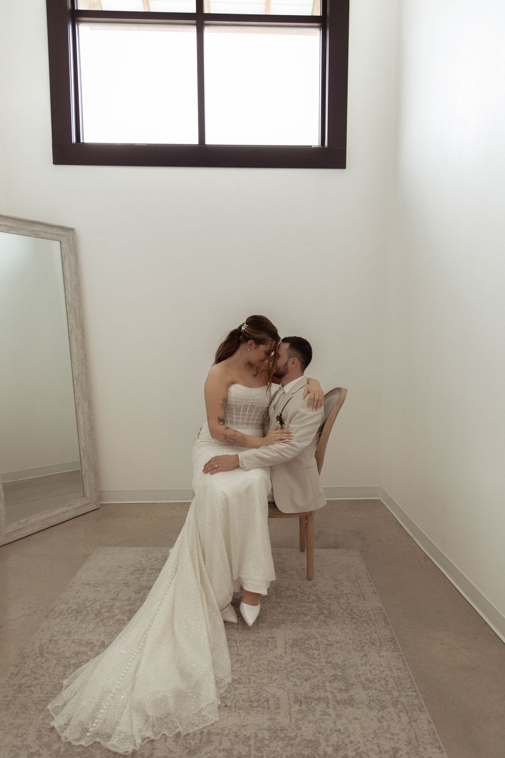 Intimate wedding photo series in a minimalist white room with a chair and window.