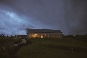Modern venue building illuminated at dusk on a hilltop location.