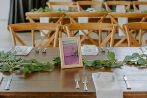 Wedding reception table details with floral greenery and place settings.