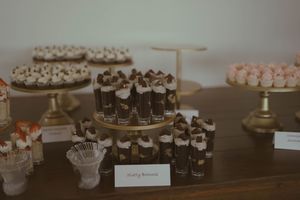 Wedding favors and treats displayed on a dark wooden table at reception.