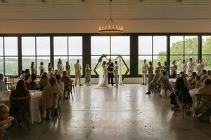 Large reception hall with guests seated at round tables and floor-to-ceiling windows.