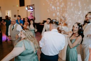 Wedding reception guests dance and celebrate under twinkling lights.