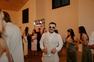 Wedding guests enjoying themselves on the dance floor at an indoor reception.