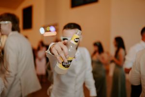 Wedding reception guests mingle and dance in a warmly lit indoor venue.