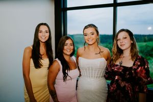 Group photo of bridesmaids in pastel dresses against a scenic outdoor backdrop.