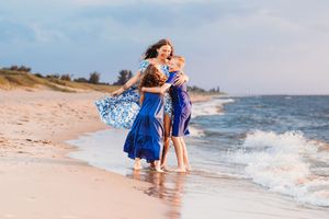 beautiful mother and her two children wearing deep blues playing in the waves on lake michigan