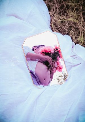 An artistic photograph showing ethereal blue fabric with an inset rose-tinted image against a natural background.