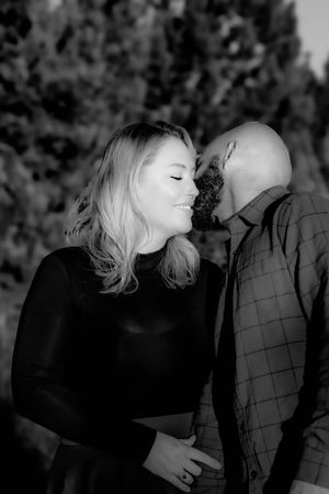 A romantic black and white portrait of a couple sharing an intimate moment together outdoors.