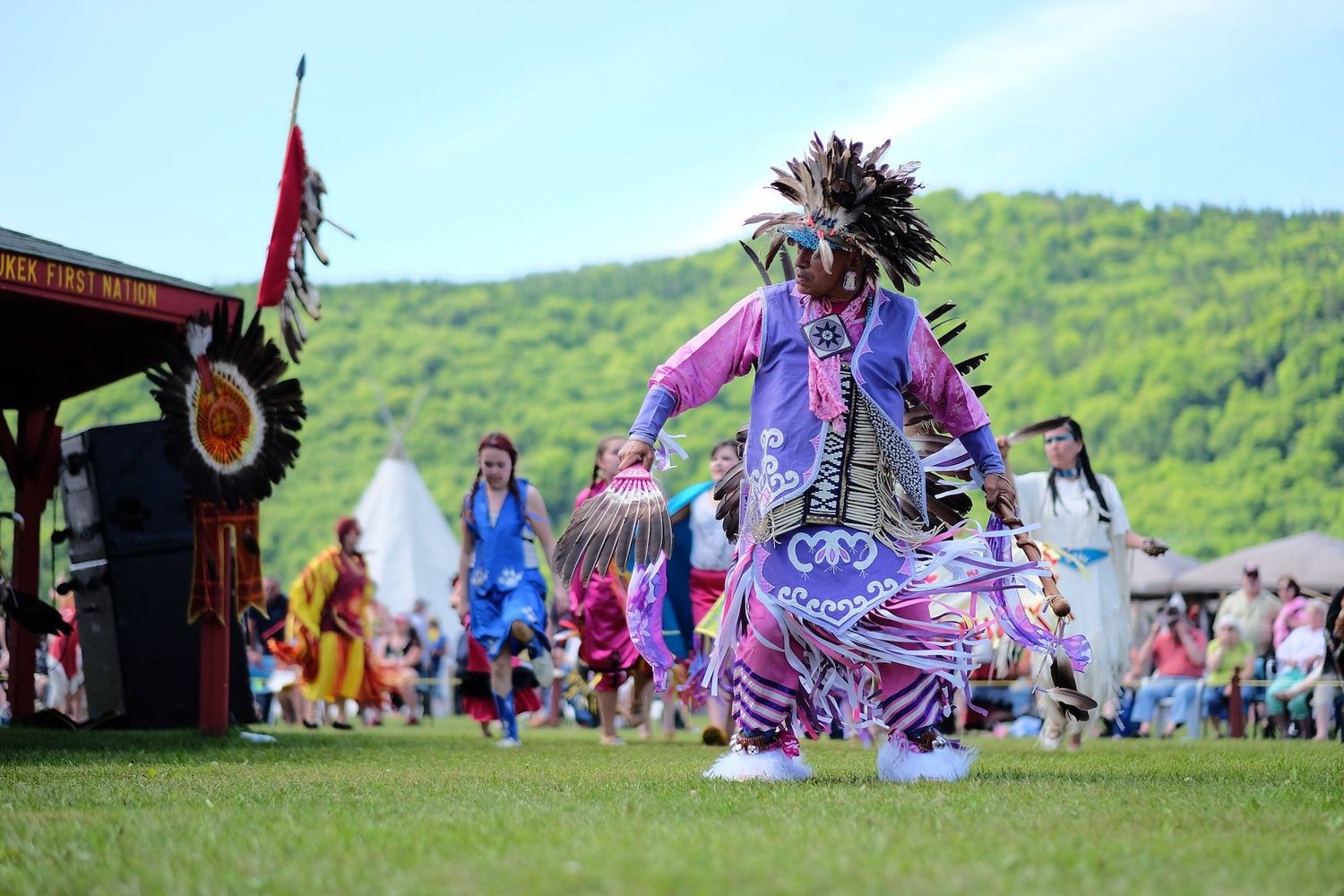A powerful photo of a Mi’kmaq powwow dancer in full regalia, captured mid-dance, showcasing the movement, colors, and cultural significance