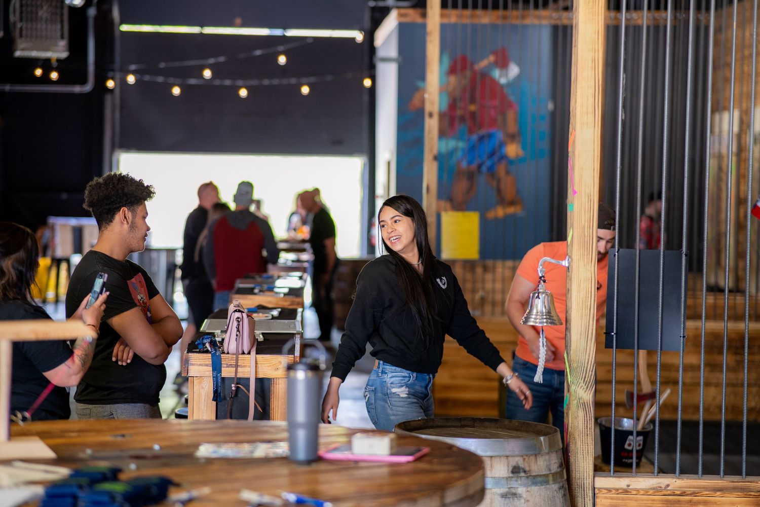 People seated at a bar counter inside a casual restaurant with hanging string lights and colorful wall art.