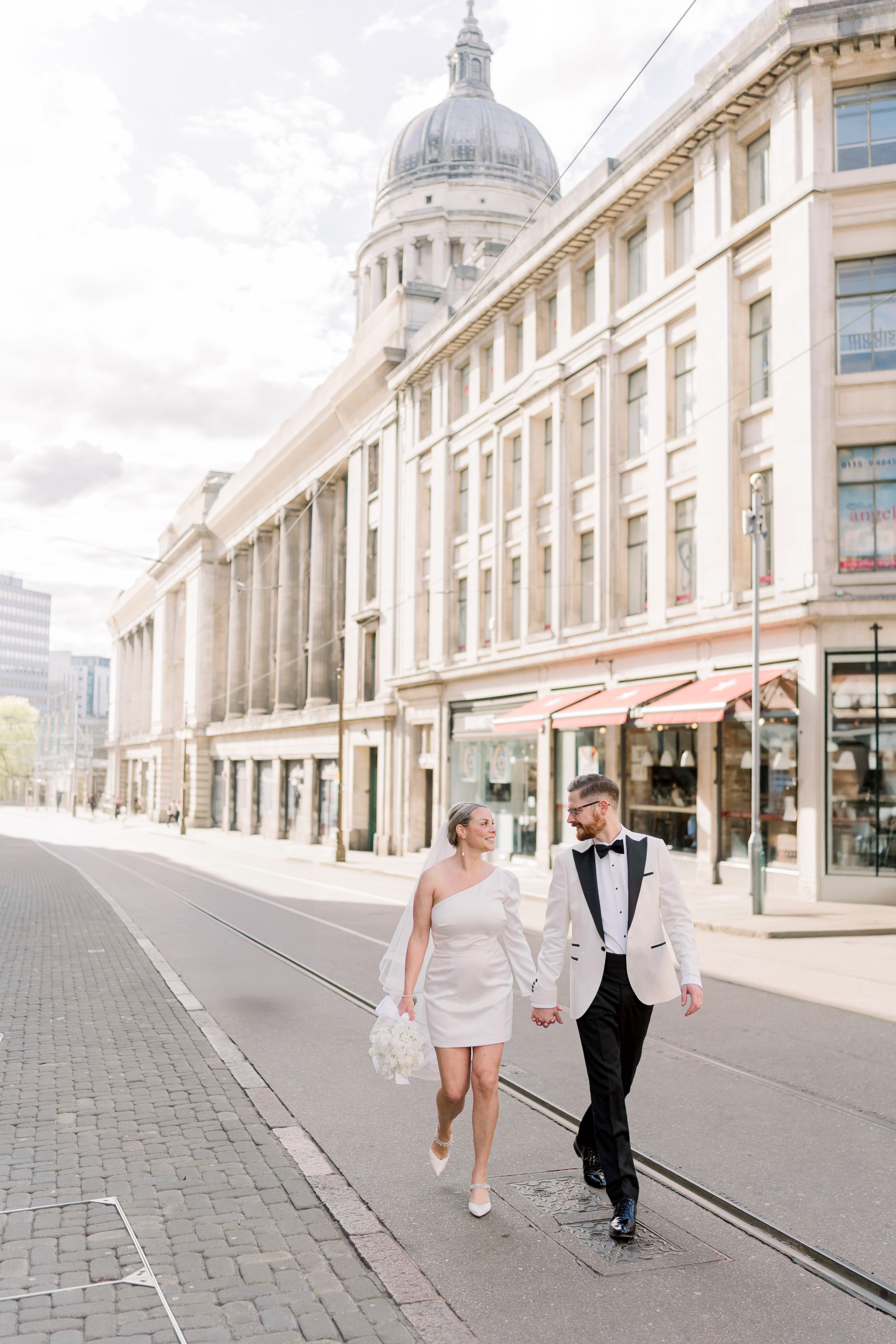 Bride and groom walk hand-in-hand outside Nottingham Council House near Hockley and the Lace Market during their spring-summer elopement.