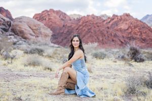 A casual desert portrait at Red Rock Canyon with dramatic red mountains and desert brush in the background.