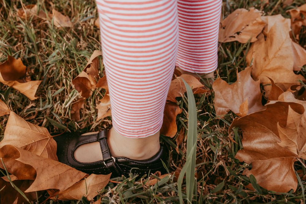 Little feet stepping on fall leaves, black Mary janes, pink leggings, Whitney Popp photographer
