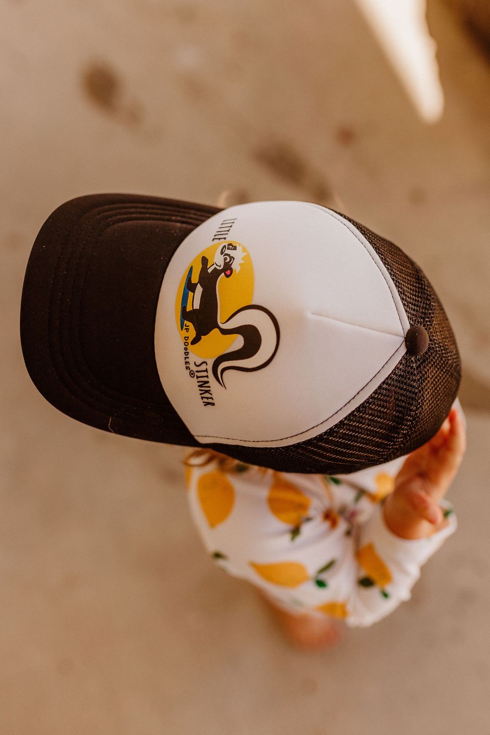 Child in backward hat with swimsuit, hat has a skunk on it, emotive photo, Whitney Popp photographer