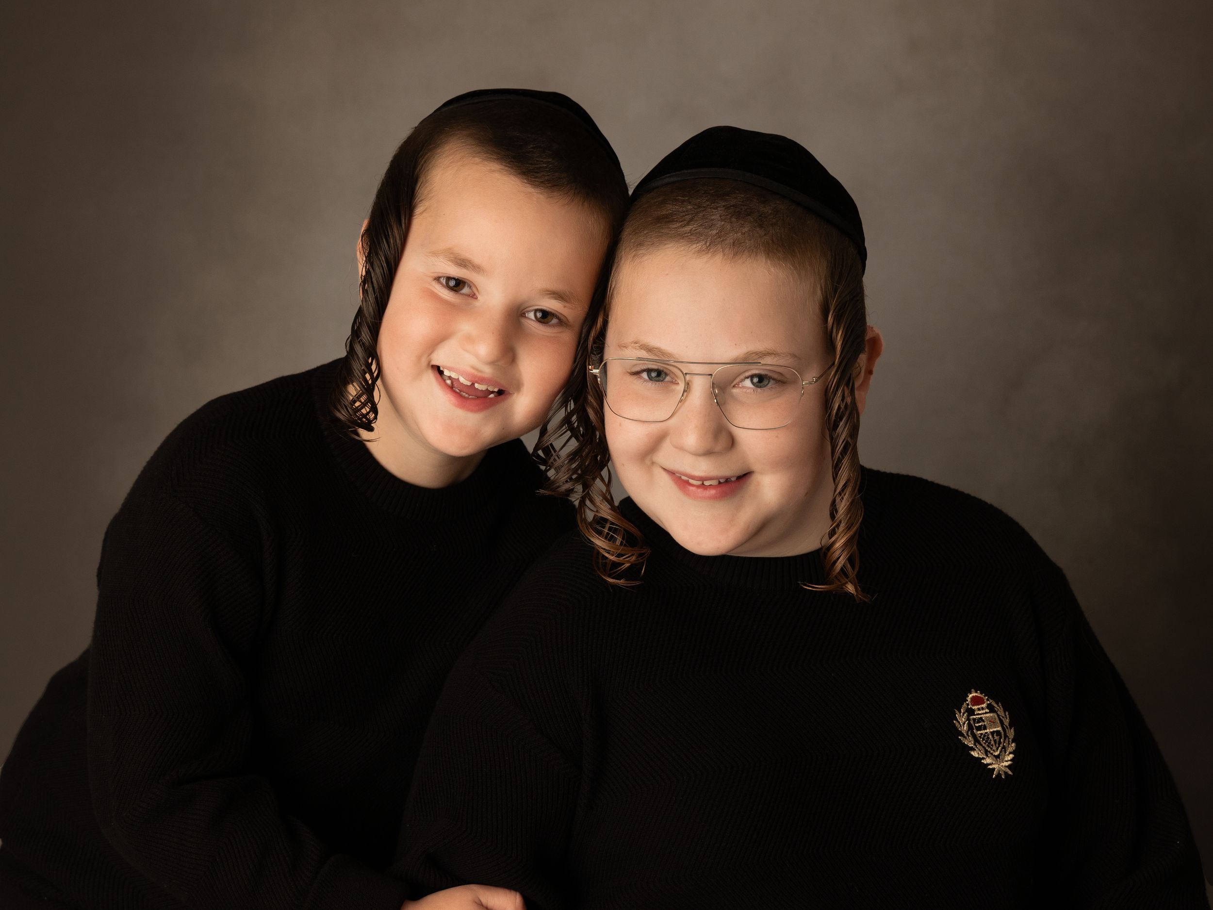 Dark studio portraits showing warm expressions and close interactions in dramatic lighting.
