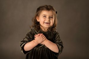 Studio portrait in dark velvet dress against moody brown background.