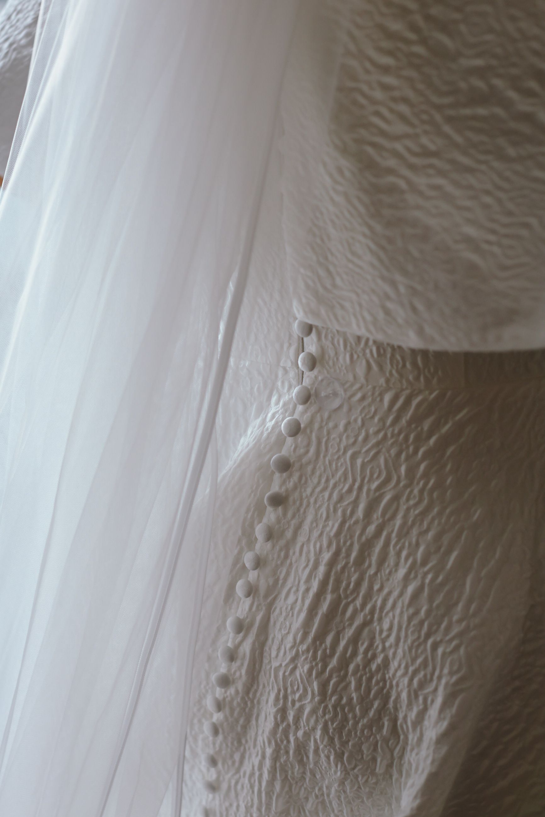 Close-up abstract view of textured white wallpaper with subtle grooves and ridges creating a rippling pattern.