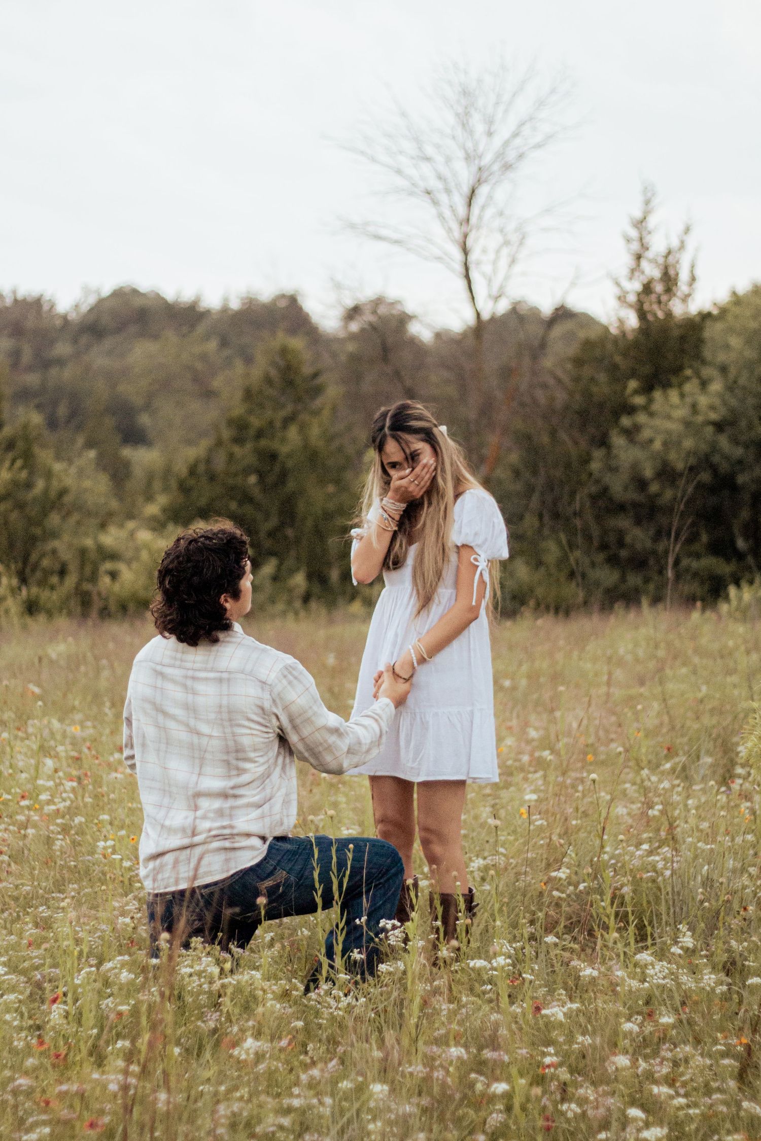 A person proposes to another in a wildflower meadow on a sunny autumn day.