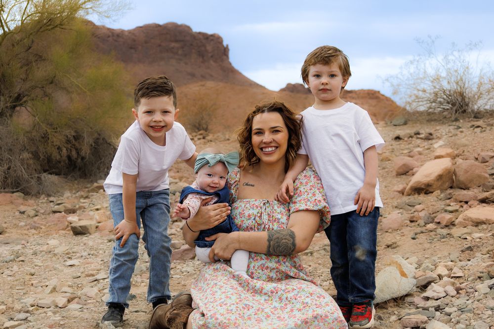 Family portrait in desert landscape with rocky mountain backdrop.