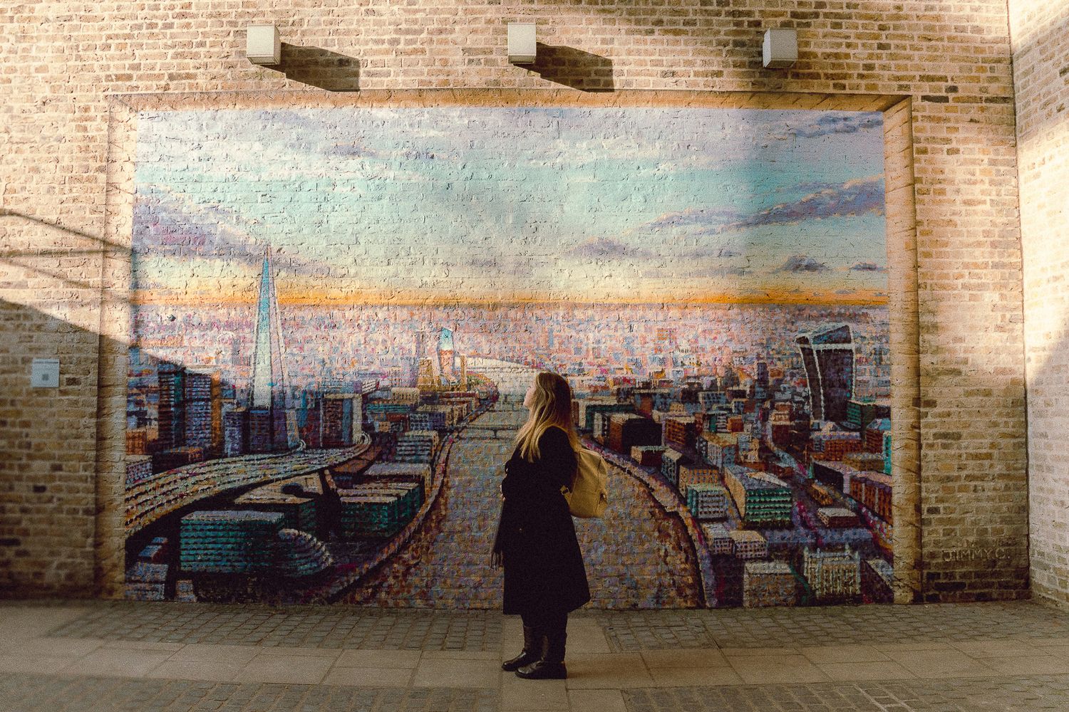 Silhouette views urban street art mural depicting a cityscape on brick wall.