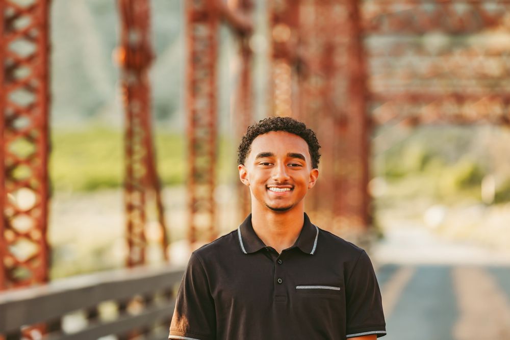 Four casual professional headshots of a smiling person against a blurred brick wall and outdoor background.