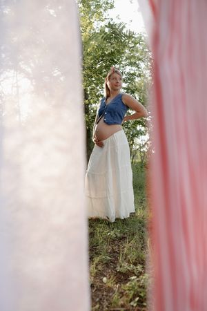 Four artistic maternity photos showing a pregnant woman in blue and white dresses against a dreamy outdoor background.