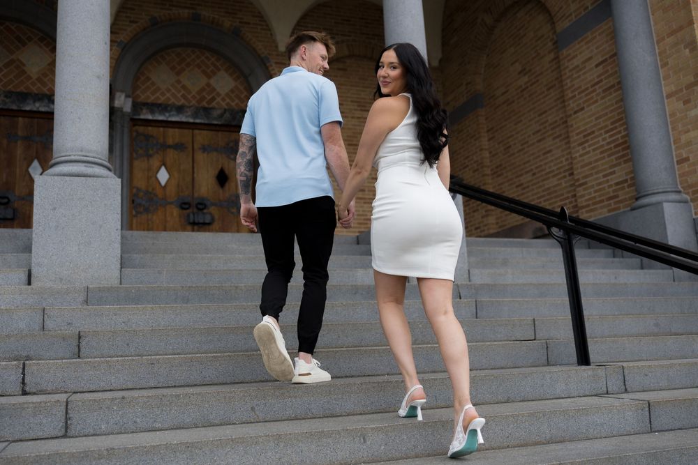 A couple walks up elegant stone stairs together at an outdoor venue.
