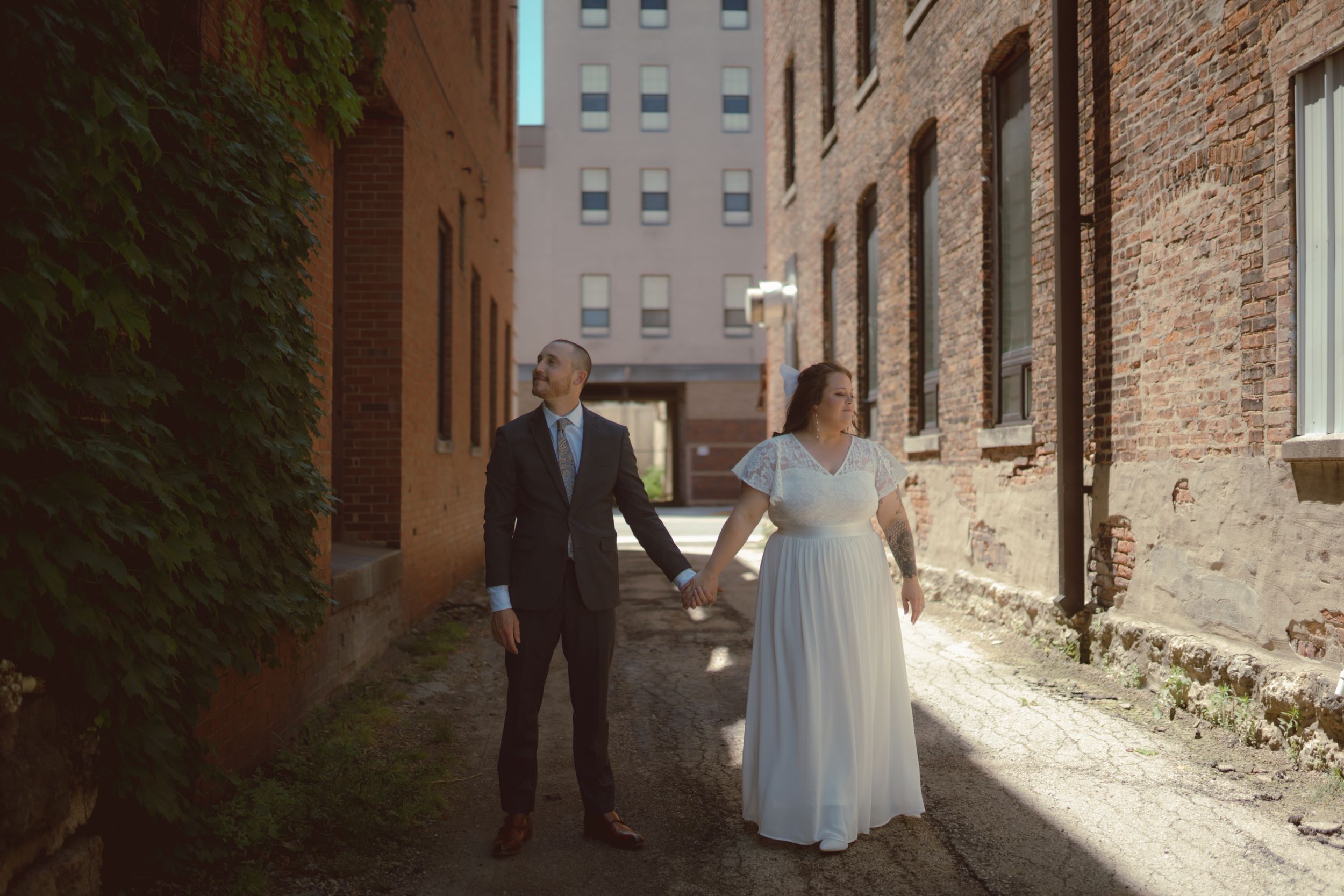 A romantic wedding photo session in an urban alleyway with brick walls and natural lighting.