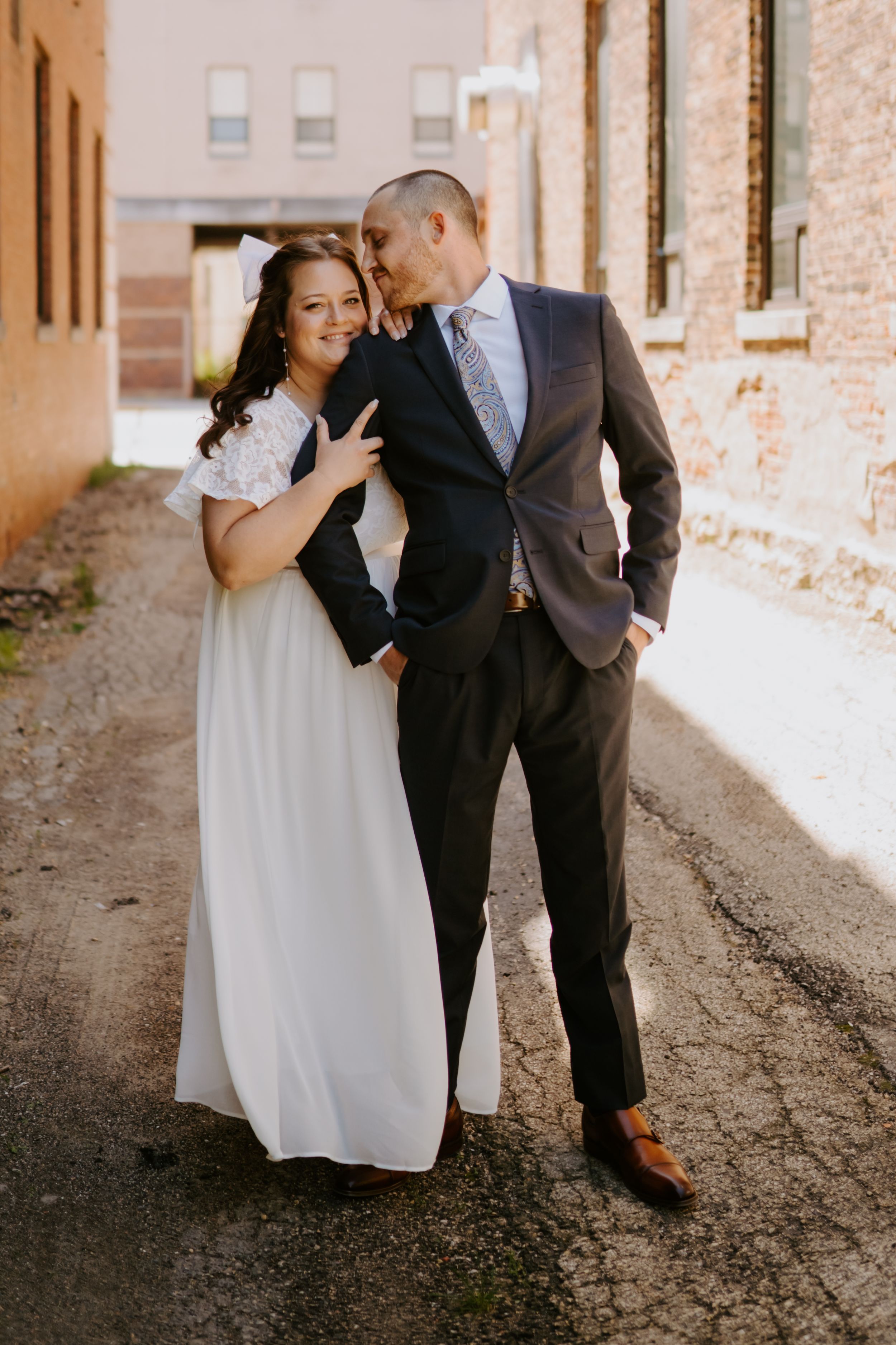 Artistic wedding photography capturing tender moments against weathered brick walls.
